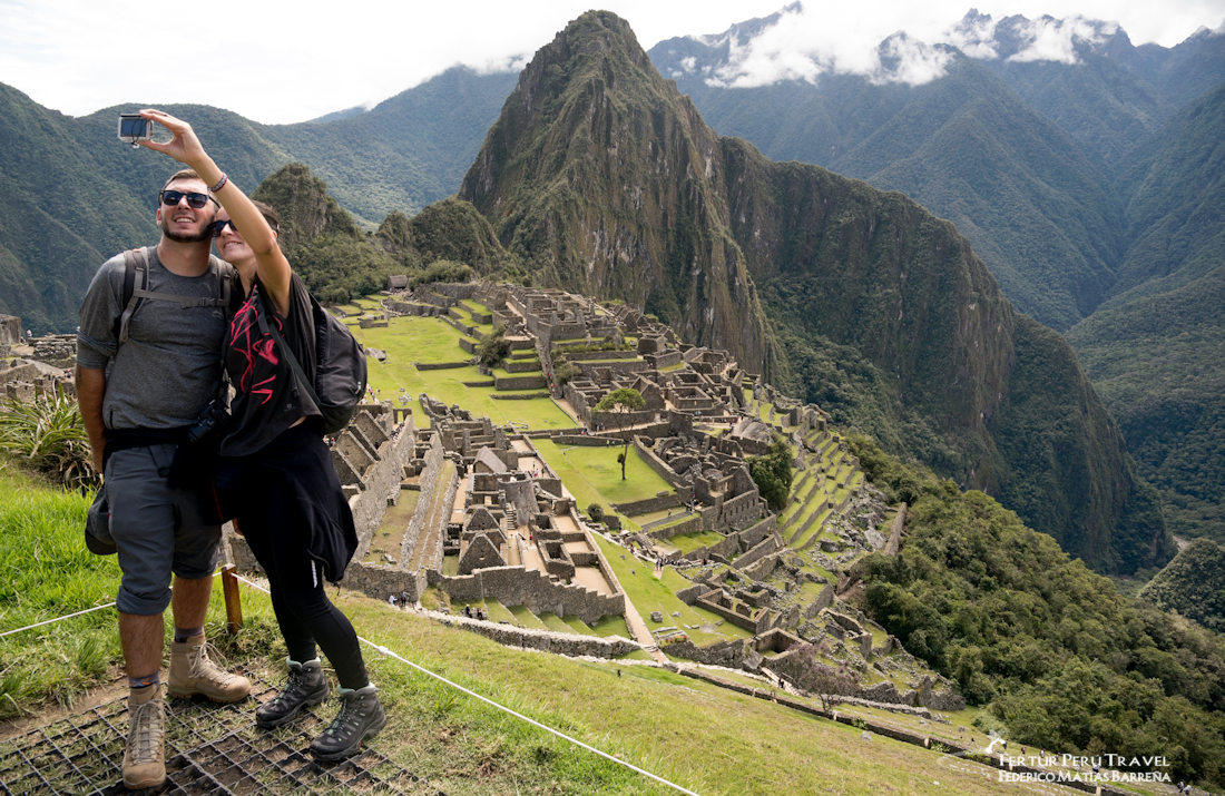 A couple take a selfie at Machu Picchu with the iconic Huayna Picchu Peak in the background