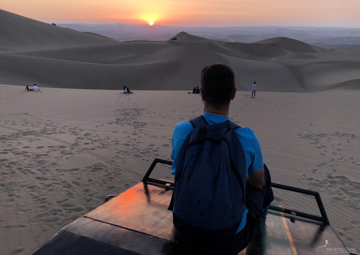 A Fertur Peru Travel client witnesses the stunning sunset over the dunes above the Huachina Oasis in Ica, Peru